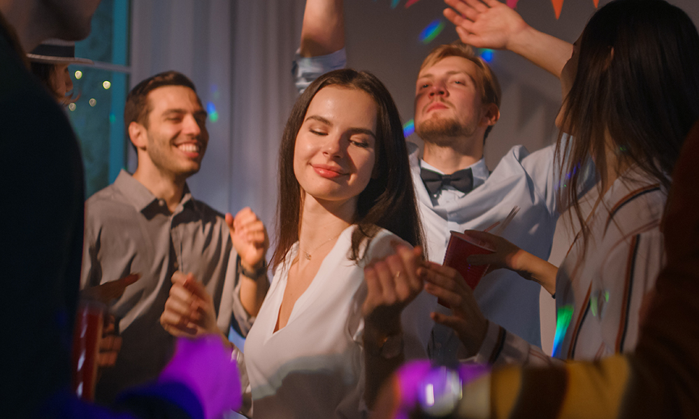 Egy csapat táncol egy bulin, középen egy nő, aki élvezi a zenét.